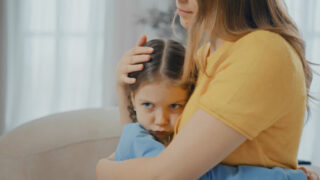 不安そうな子供を抱きしめる大人