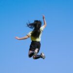 青空背景に元気良くジャンプする女の子