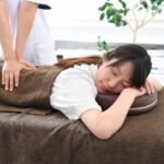 ベッドでマッサージ(整体)を受ける若い女性