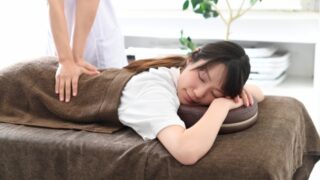 ベッドでマッサージ(整体)を受ける若い女性