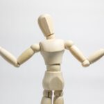 両手を広げて肩をすくめる木製の人形